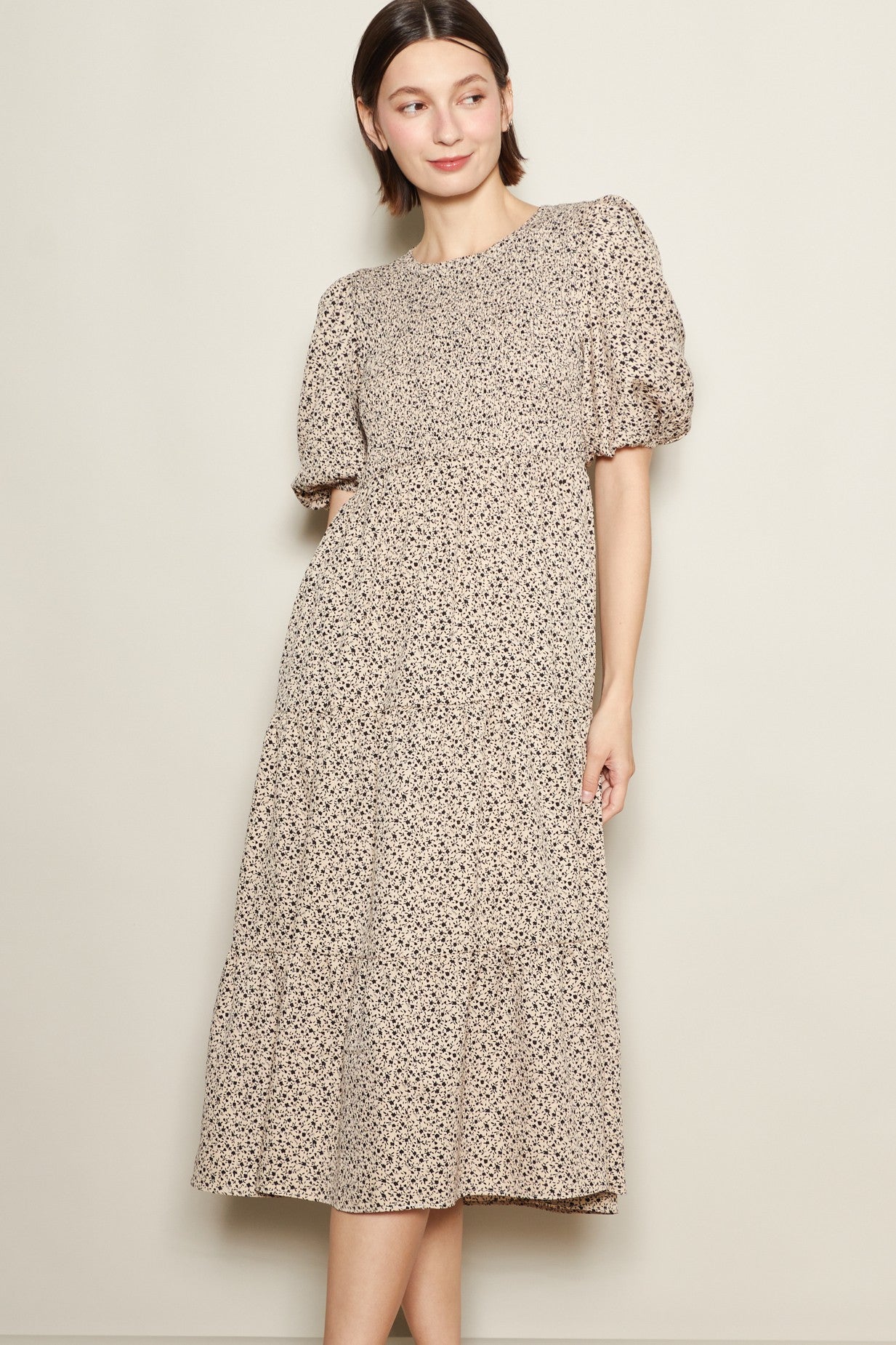 woman wearing a beige floral midi dress with puff sleeves and a tiered skirt