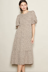 woman wearing a beige floral midi dress with puff sleeves and a tiered skirt