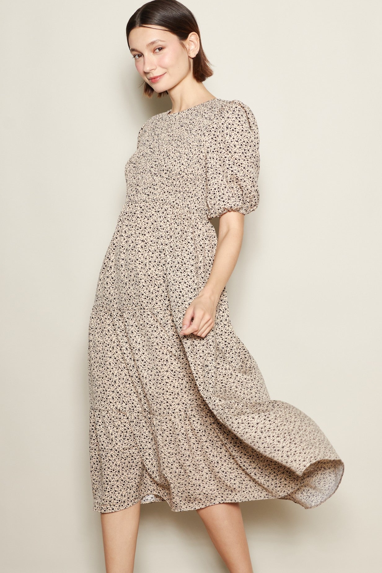 woman wearing a beige floral midi dress with puff sleeves and a smocked bodice