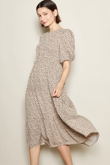 woman wearing a beige floral midi dress with puff sleeves and a smocked bodice