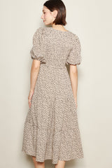 woman wearing a beige floral midi dress with puff sleeves and a tiered skirt, showing the back view