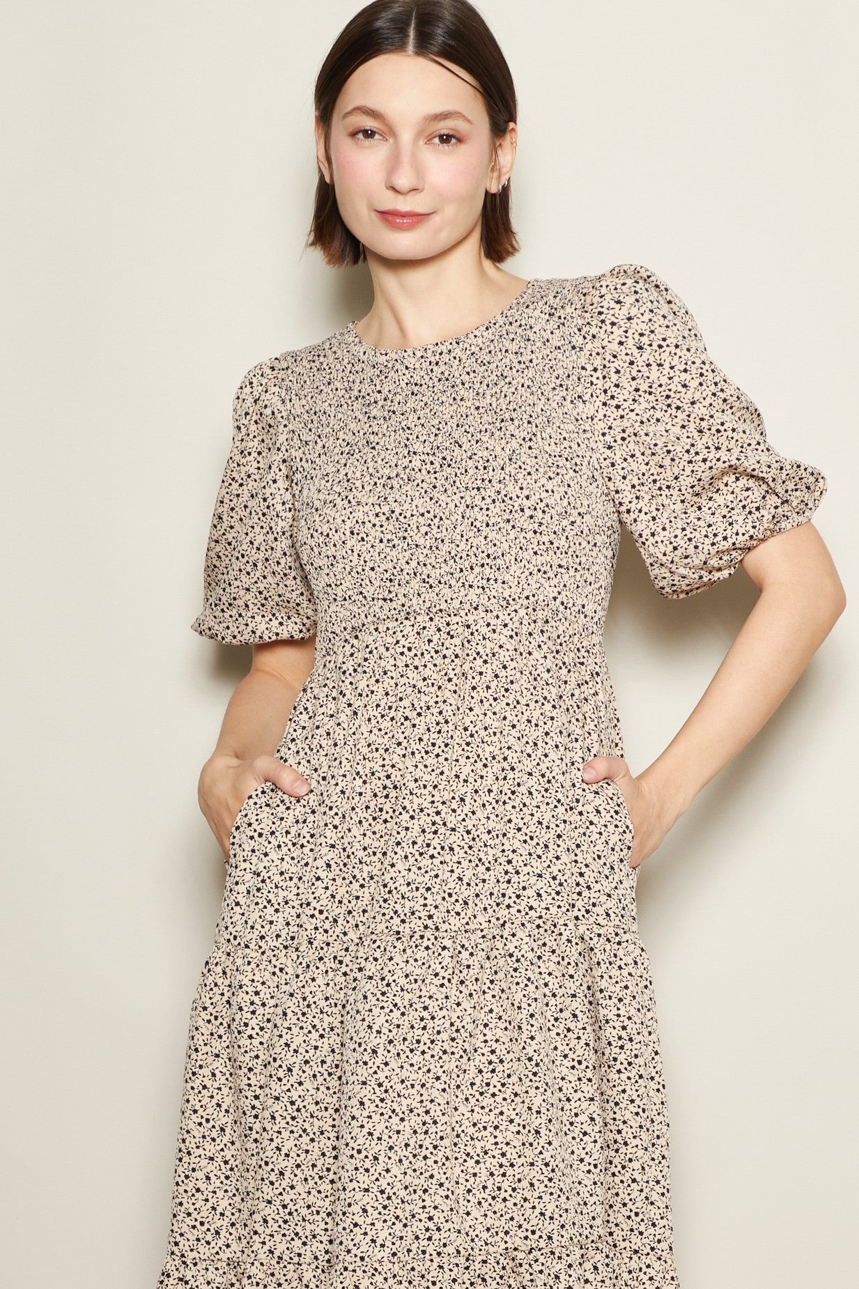 woman wearing a beige floral print puff sleeve dress with pockets