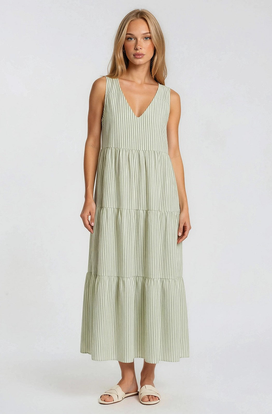 woman wearing a light green striped maxi dress with a V-neck and tiered skirt