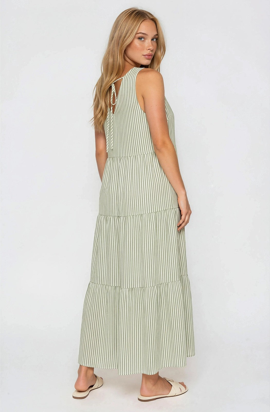 woman wearing a green and white striped maxi dress with tiered design and open back detail