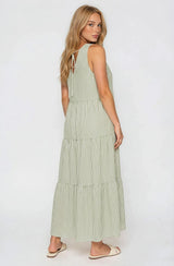 woman wearing a green and white striped maxi dress with tiered design and open back detail