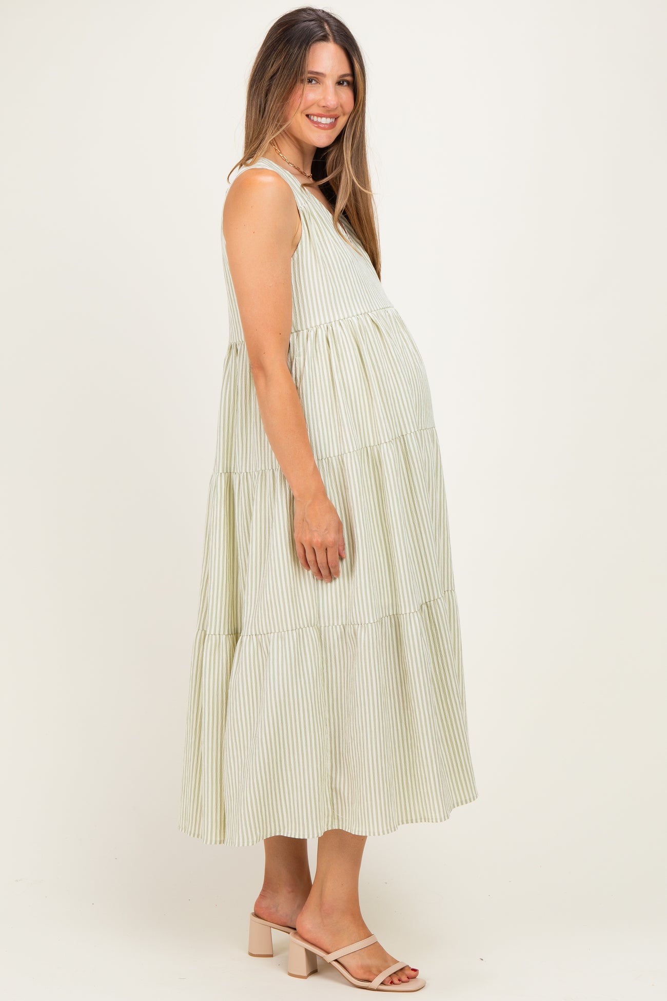 woman wearing a green and white striped maternity maxi dress with a tiered design and visible baby bump