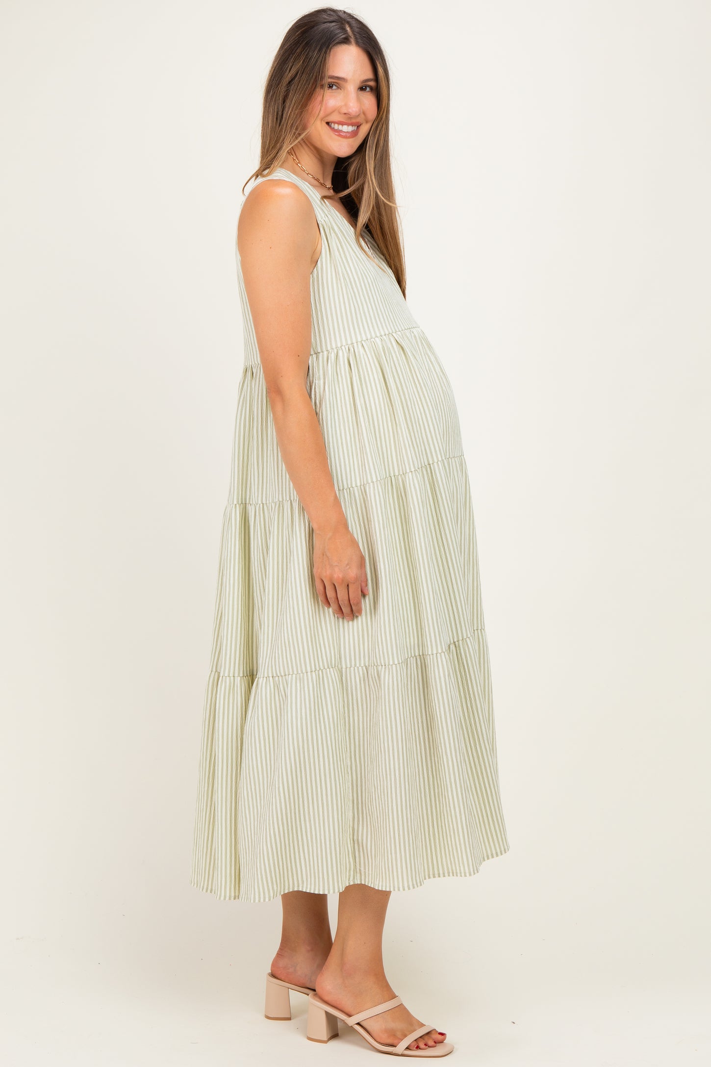 woman wearing a green and white striped maternity maxi dress with a tiered design and visible baby bump