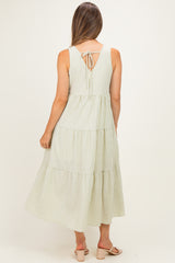 woman wearing a green and white striped maternity dress with a tiered skirt and tie detail at the back