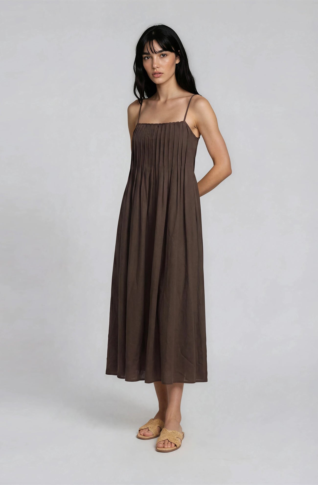 woman wearing a brown sleeveless midi dress with a gathered bodice and relaxed fit