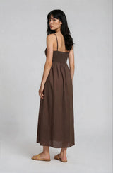 woman wearing a brown maxi dress with a smocked bodice and spaghetti straps, viewed from the back