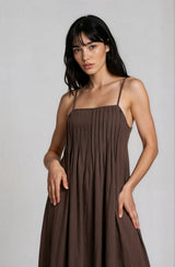 woman wearing a sleeveless brown pleated dress with thin straps