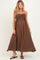 woman wearing a brown maternity maxi dress with adjustable spaghetti straps and a pleated bodice, showing her baby bump