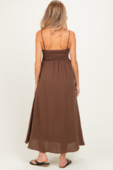 woman wearing a brown maternity maxi dress with a smocked back and thin straps, showing off her baby bump