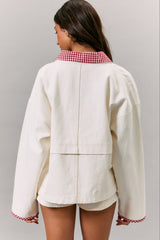 woman wearing a cream oversized jacket with a red gingham collar, seen from the back