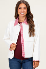 woman wearing a white maternity jacket with red gingham details and a maroon top, smiling at the camera