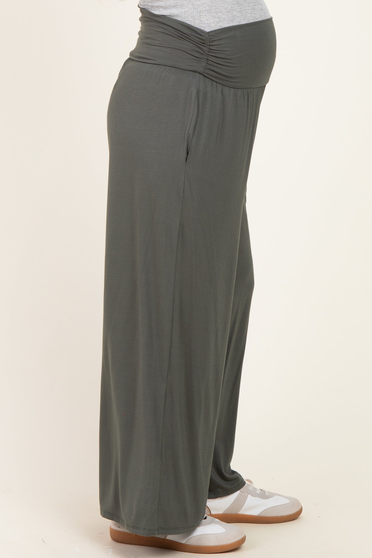 woman wearing a pair of dark green maternity wide-leg pants with a gathered waistband and visible baby bump