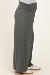 woman wearing a pair of dark green maternity wide-leg pants with a gathered waistband and visible baby bump