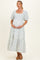 woman wearing a blue patterned maternity dress with puff sleeves and a tiered skirt, cradling her baby bump