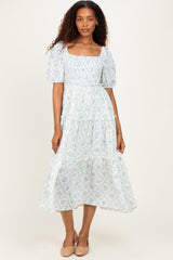 woman wearing a light blue floral puff sleeve midi dress with tiered ruffles and a square neckline