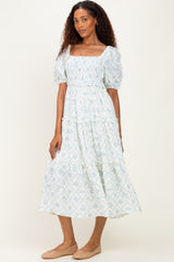 woman wearing a light blue floral printed puff sleeve midi dress with a square neckline and tiered ruffle skirt