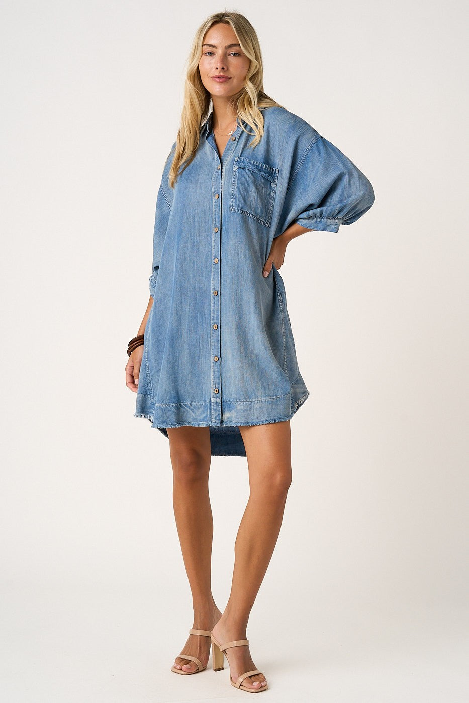 woman wearing a denim button-up shirt dress with a front pocket and rolled-up sleeves