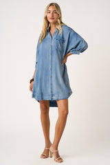 woman wearing a denim button-up shirt dress with a front pocket and rolled-up sleeves