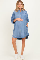woman wearing a light blue denim maternity shirt dress with a baby bump and pockets, styled with white sneakers