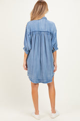 woman wearing a light blue maternity denim shirt dress with a relaxed fit and rolled sleeves, showing the back view