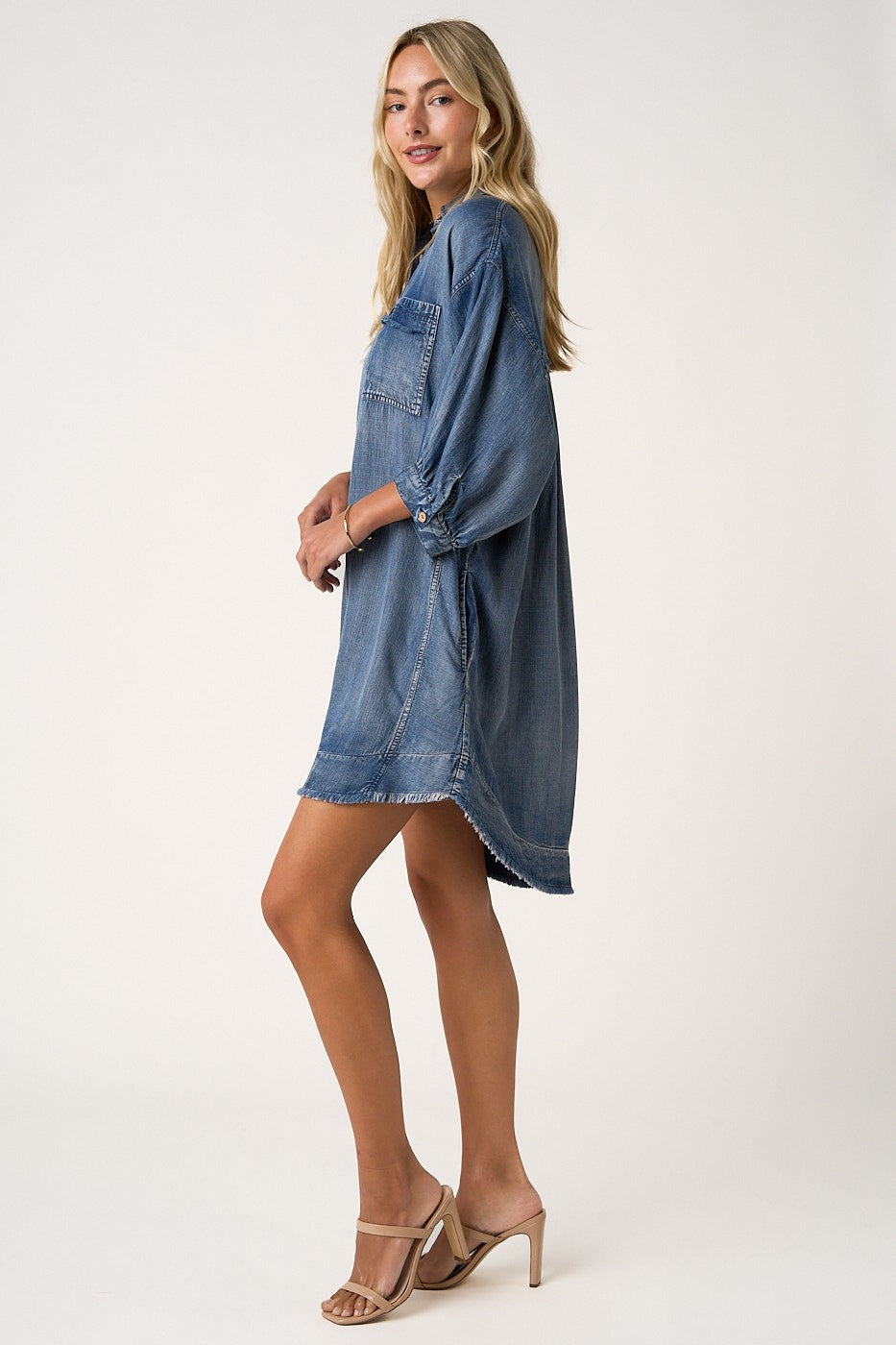 woman wearing a loose-fitting denim shirt dress with three-quarter sleeves and a front pocket