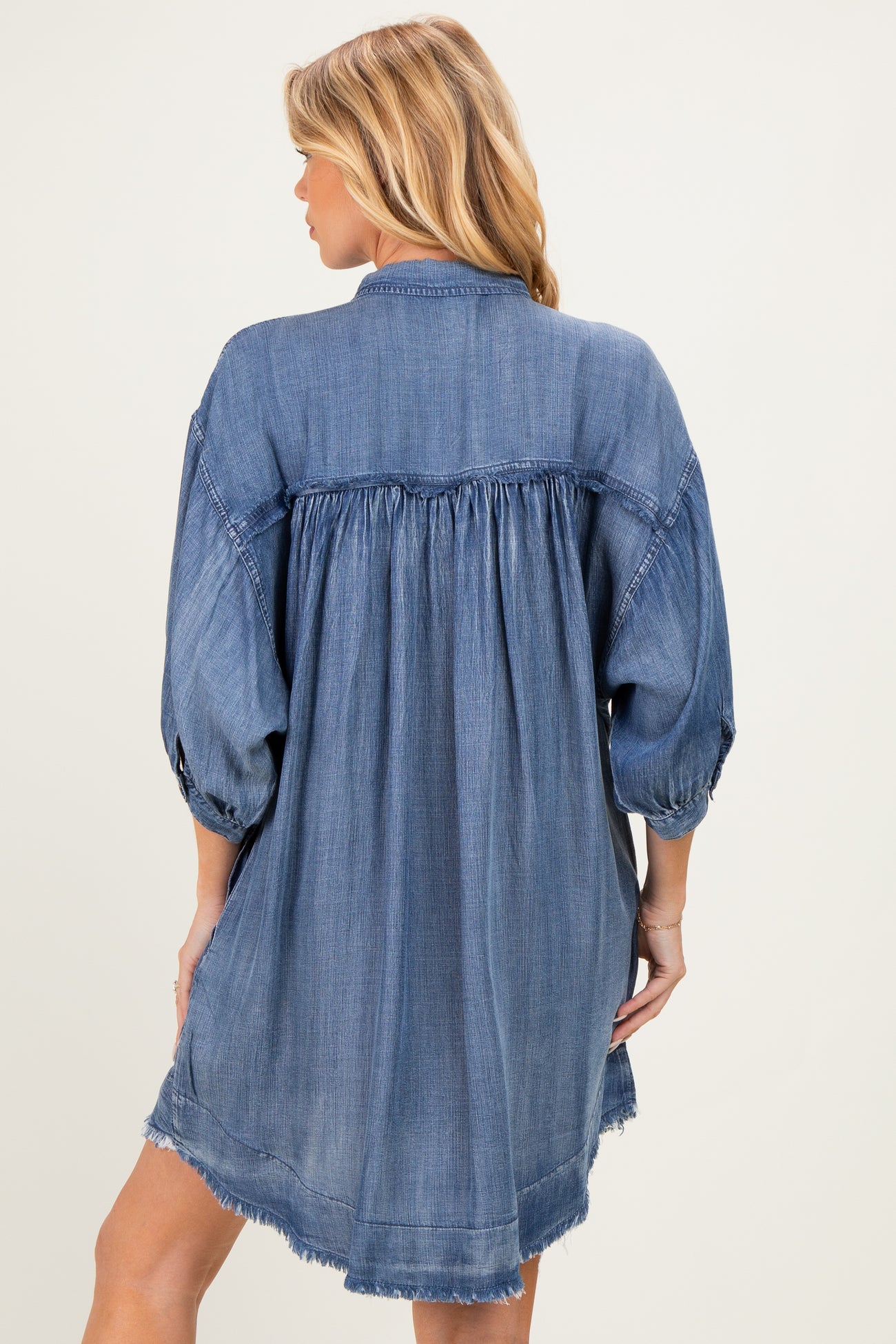 woman wearing a denim maternity shirt dress with a flowy back and puffed sleeves, showing a relaxed fit