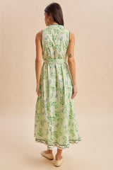 woman wearing a green sleeveless maxi dress with a floral pattern and a belted waist, viewed from the back
