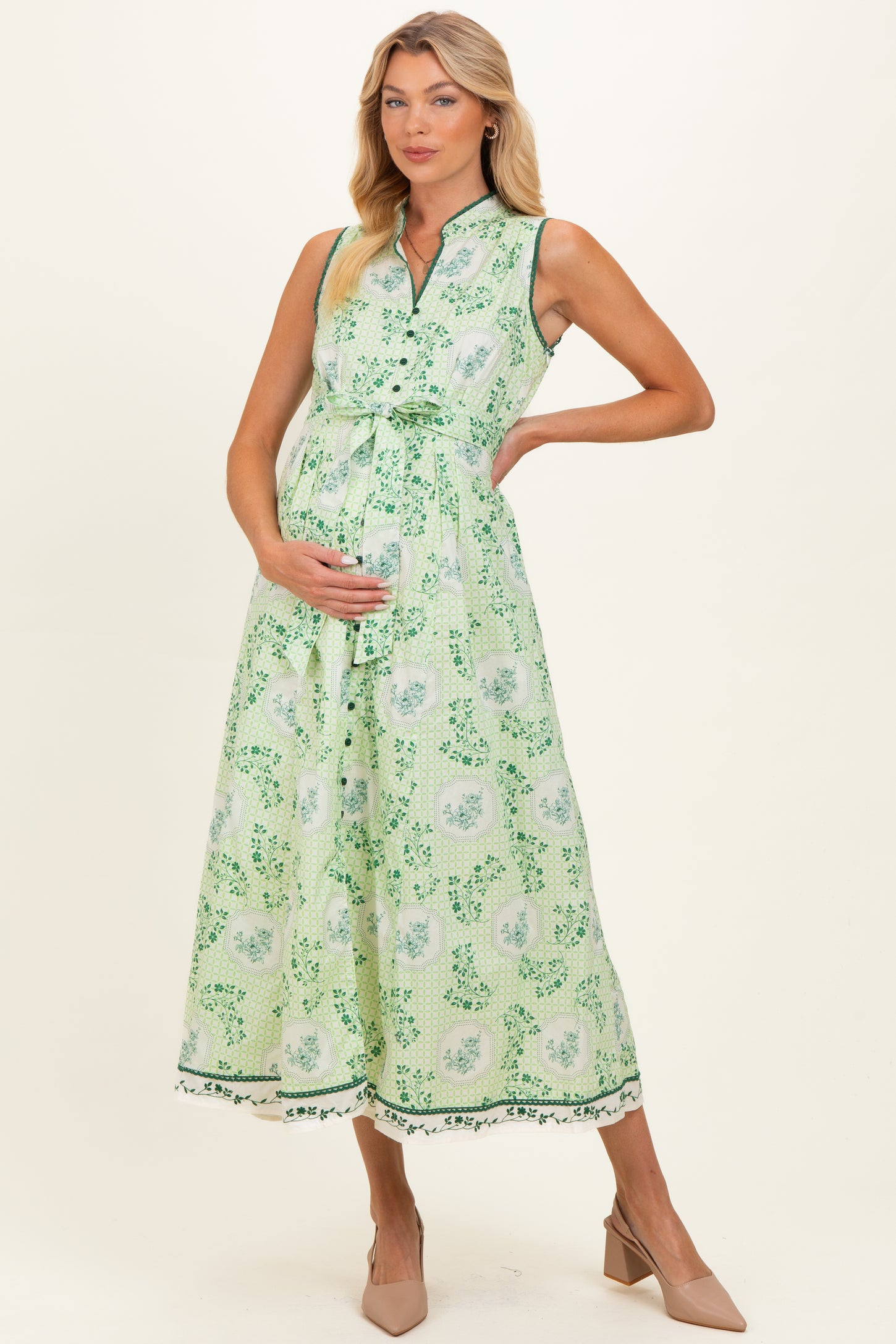 woman wearing a green floral maternity dress with a tie waist and a visible baby bump