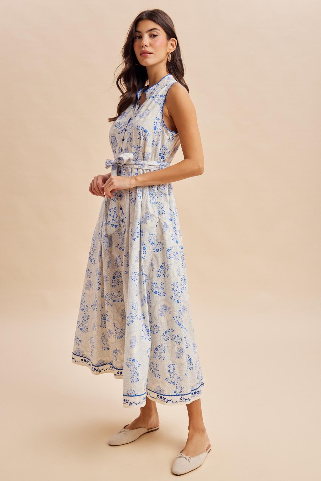 woman wearing a light blue floral print midi dress with a belted waist and a high neckline