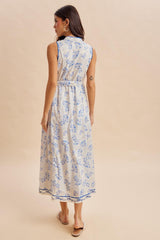 woman wearing a sleeveless maxi dress with a floral print in blue and cream, viewed from the back
