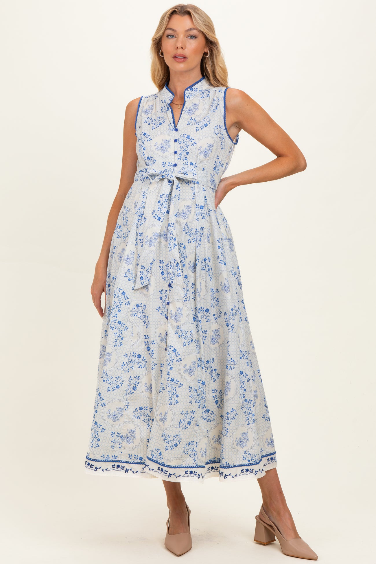 woman wearing a blue and white floral print maternity maxi dress with a tie waist and sleeveless design