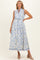 woman wearing a blue and white floral print maternity maxi dress with a tie waist and sleeveless design