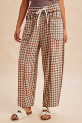 woman wearing brown and white checked wide-leg pants with an elastic waistband and pockets