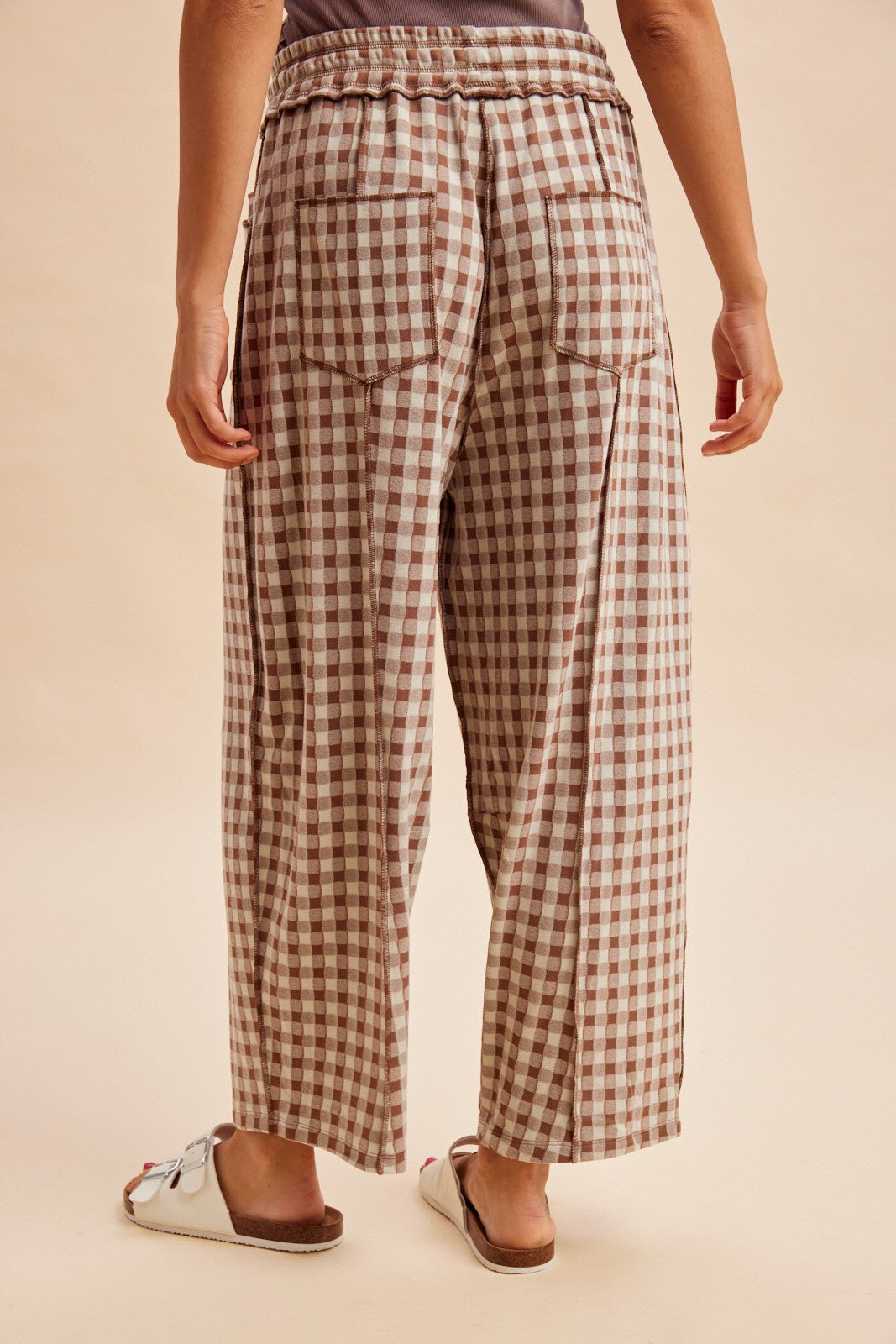 woman wearing brown and cream oversized checkered wide-leg pants, view from the back