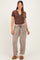 woman wearing a brown henley maternity top and checkered lounge pants, with a visible baby bump