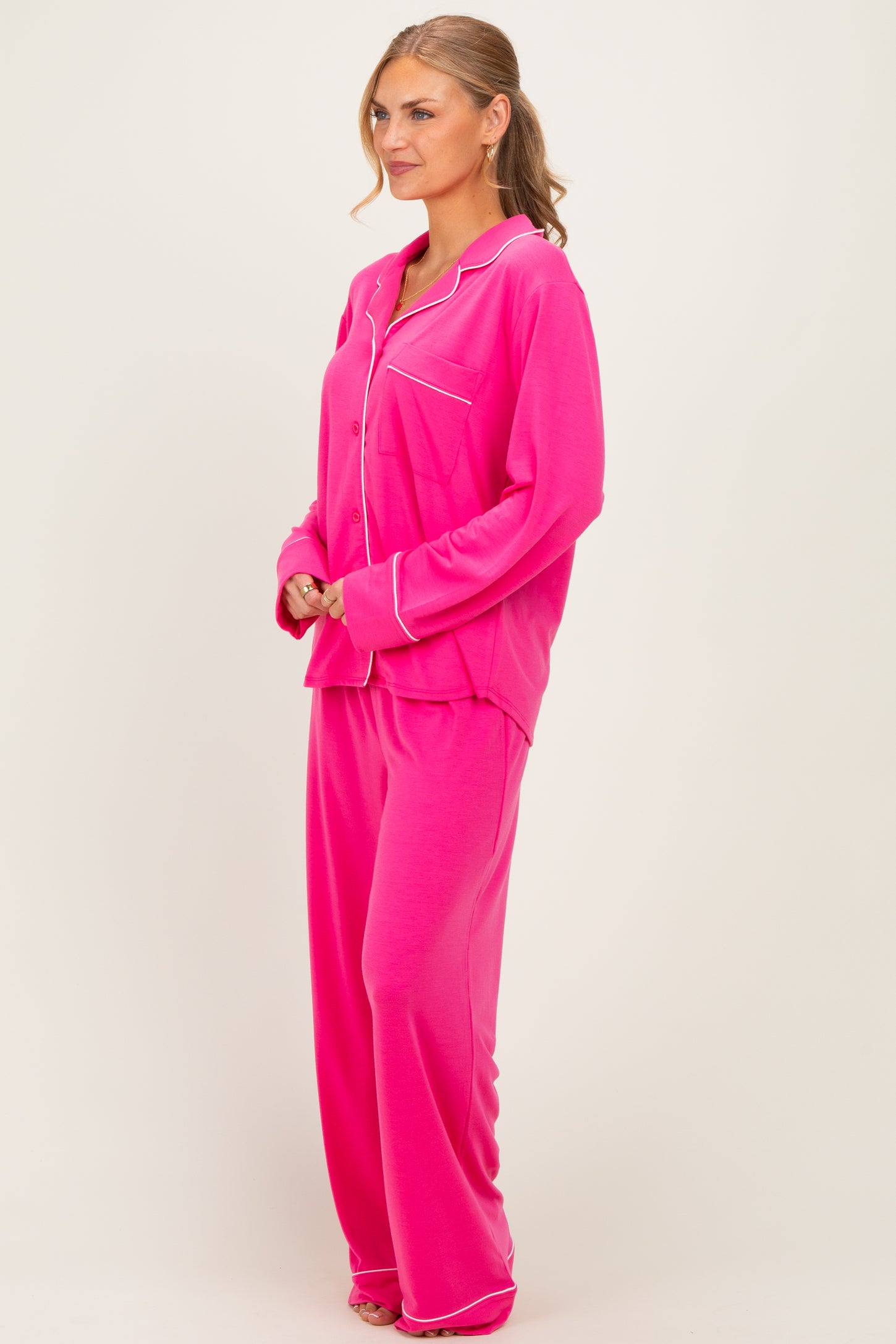 woman wearing a bright pink pajama set with a long sleeve button-up top and loose-fitting pants