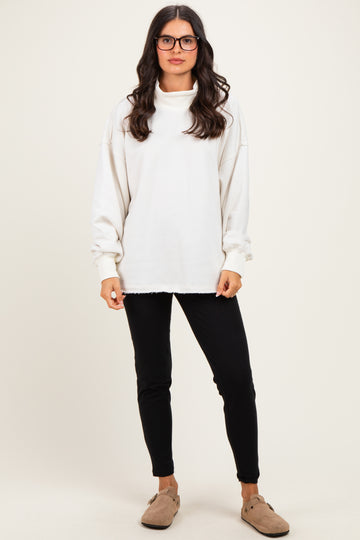 woman wearing a white oversized sweatshirt with a cowl neck and black skinny pants