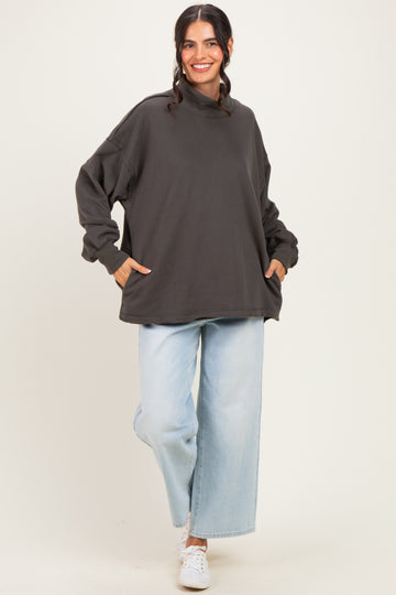 woman wearing an oversized dark gray sweatshirt with side pockets and light blue wide-leg jeans