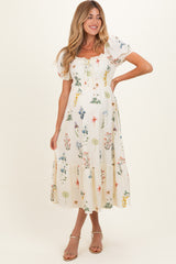woman wearing a floral print maternity maxi dress with short puff sleeves and a tiered hemline