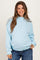 woman wearing a light blue maternity sweatshirt with a ruffled hem and a visible baby bump