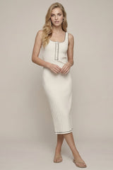 woman wearing a cream ribbed midi dress with button details and black trim, standing against a neutral background