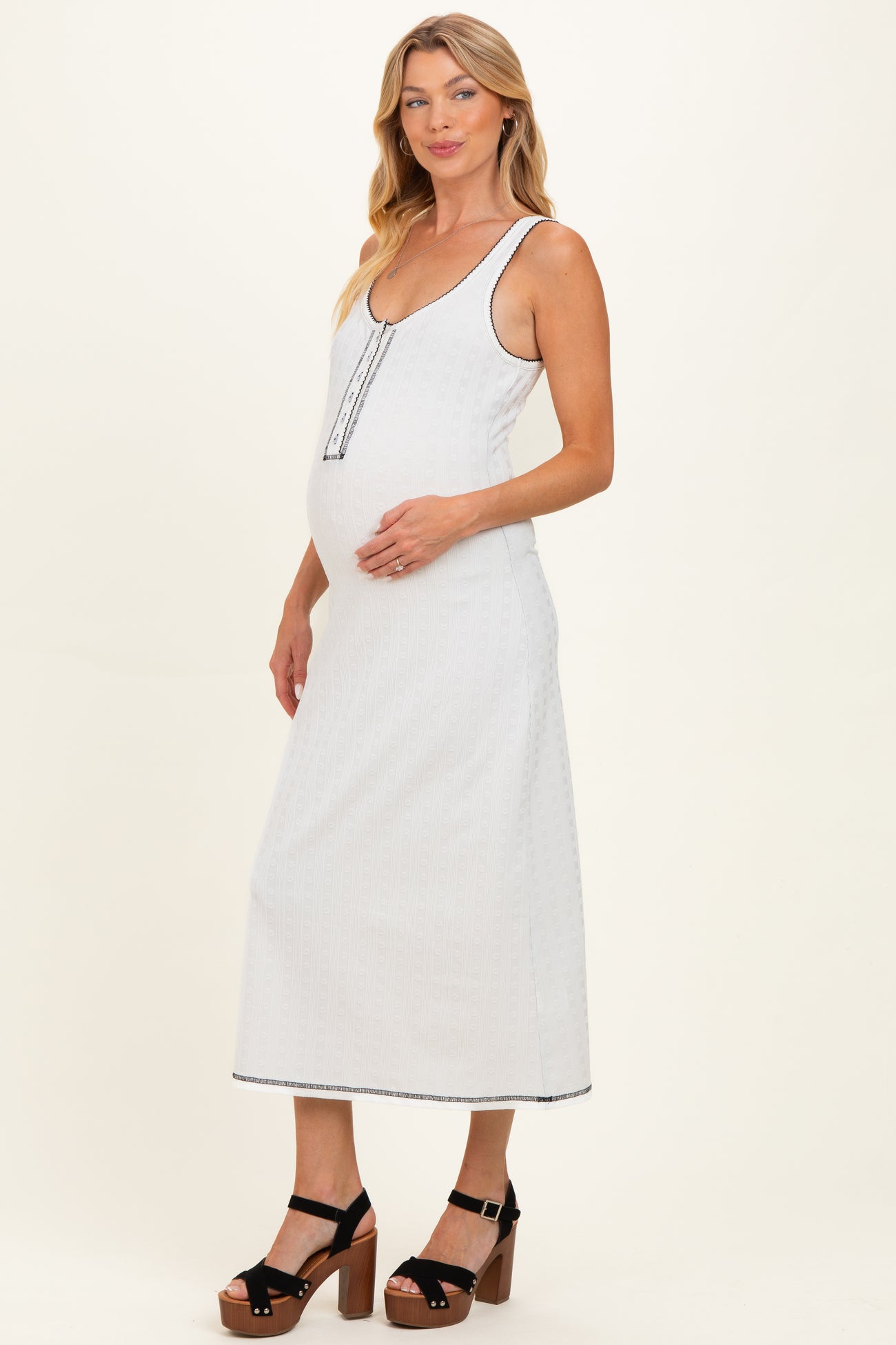 woman wearing a light gray maternity maxi dress with a scoop neckline and button details, highlighting her baby bump