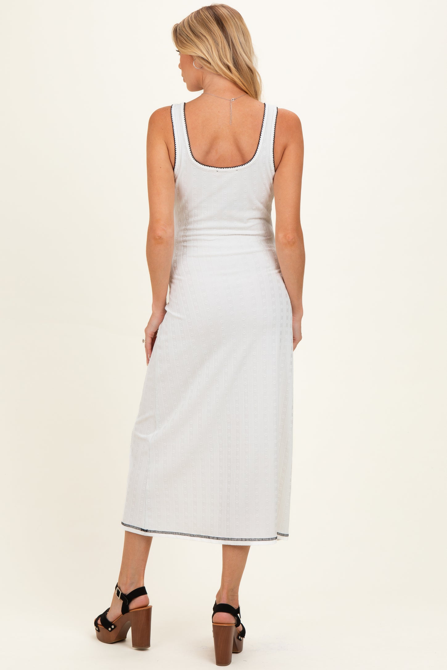 woman wearing a white ribbed maternity maxi dress with a scoop back and side slit, showing her baby bump