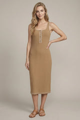 woman wearing a beige ribbed midi dress with a button-down front and spaghetti straps, standing with one hand on her hip