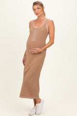 woman wearing a brown ribbed maternity dress with buttons, gently holding her baby bump