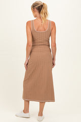 woman wearing a brown ribbed maternity dress with a fitted silhouette, showing the back view and wearing white sneakers